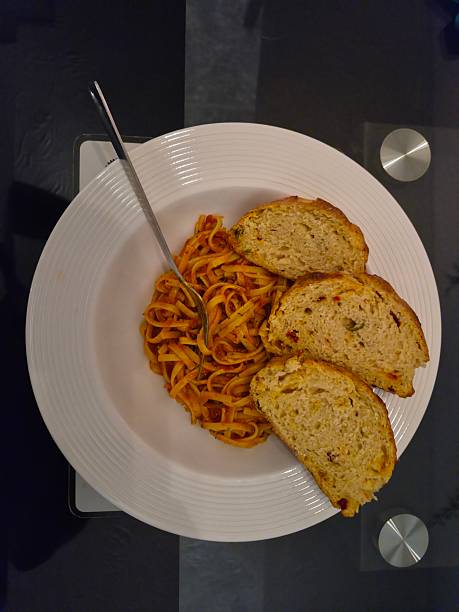 A bowl of fresh pasta in a sun dried tomato sauce with sliced freshly baked sourdough bread