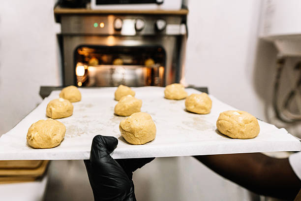 istock Person placing cookie dough on baking sheet into oven 2242553665
