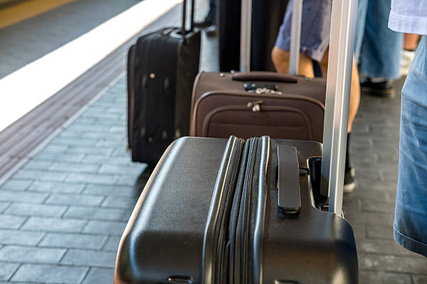Traveler with black suitcase waiting at train station platform