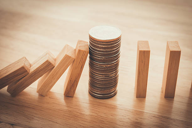 istock Stacked coins stop wood block fall domino effect on office wooden table background. 2242556887