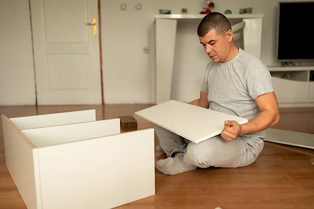 istock Man Assembling Wooden Shelf in Living Room 2242559447