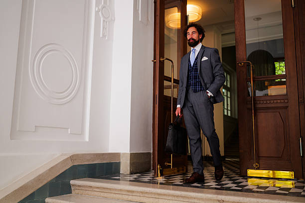 istock Elegant businessman exiting luxurious building with briefcase 2242560644