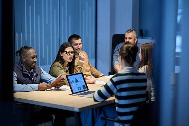 istock Diverse business team gathered around a table discussing analytics during a meeting in a modern office. Laptop screen shows charts and graphs, symbolizing teamwork, communication, and data driven strategy. 2242560765