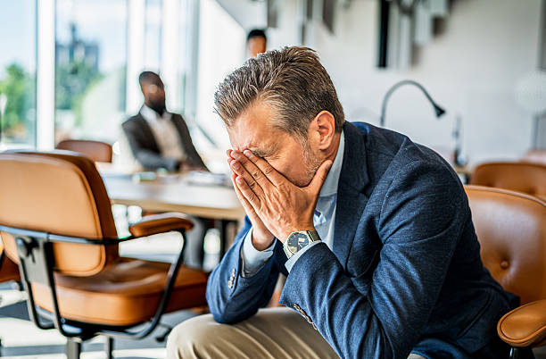 istock Stressed businessman covering face with hands in office 2242560804