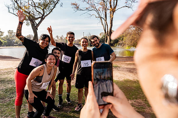 Diverse friends enjoy active outdoor fitness training workouts. Group portrait happy young and mature multiethnic men and women in sports clothes standing on city bridge, looking at camera and smiling