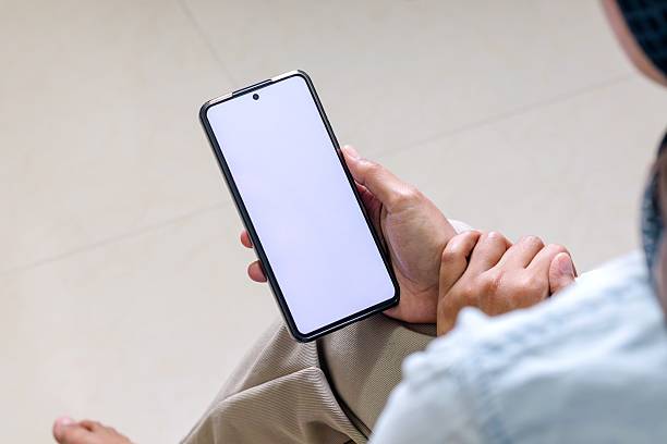 istock Woman's hand holding a smartphone with white blank screen indoors 2242562638