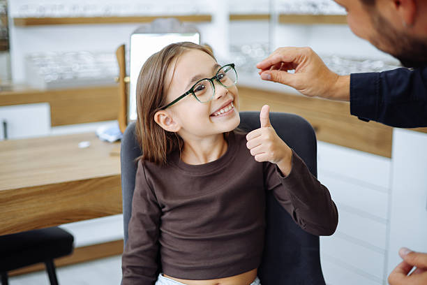 istock Lttle girl choosing new eyewear in optical store 2242565663