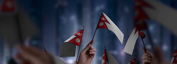 Nepal flags in their hands on a blurred urban background. The photo illustration was created without the use of artificial intelligence, only using Photoshop.