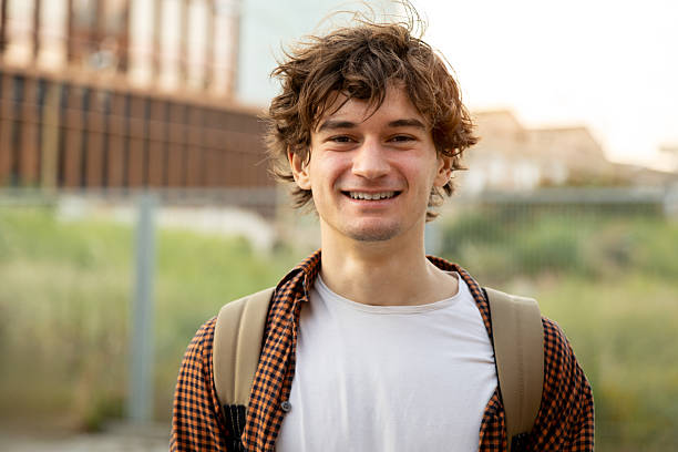 istock Portrait of a smiling young man with backpack in urban setting 2242570055