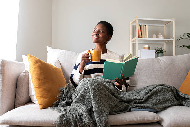 istock Woman enjoying hot drink while reading book at home 2242570488
