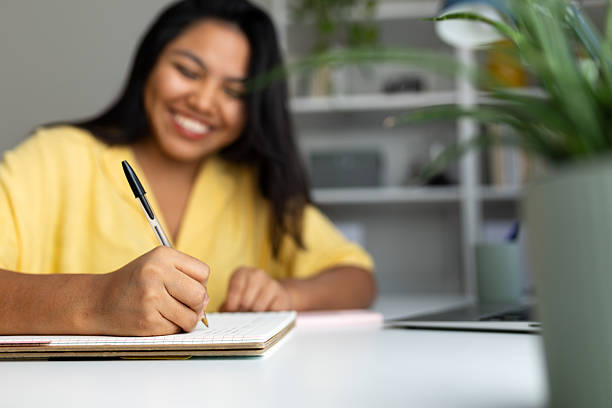 istock Latin american woman writing notes in notebook at home office desk 2242570569