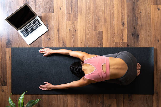 istock Woman stretching on yoga mat using laptop for online class 2242570849