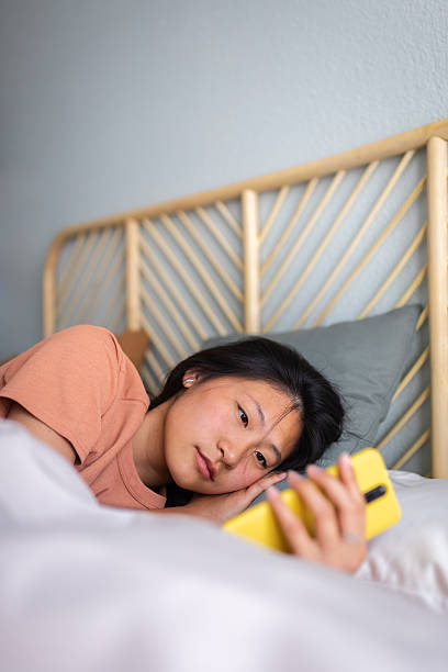 istock Young woman relaxing in bed browsing smartphone 2242570895