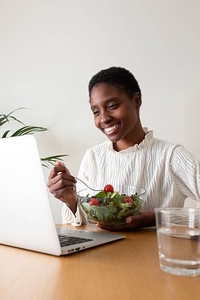 istock Young woman enjoying healthy lunch while working on laptop 2242570922