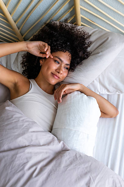 istock Woman waking up in bed feeling well-rested and happy 2242571868