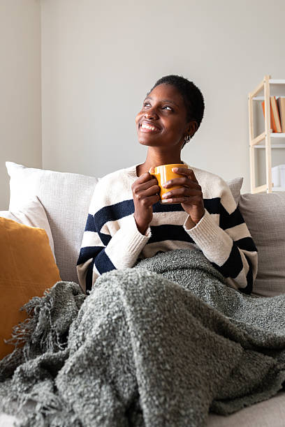 istock Young black woman relaxing on couch drinking coffee 2242573196