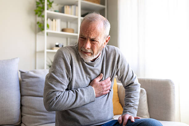 istock Senior man suffering from chest pain while sitting on sofa at home 2242574504