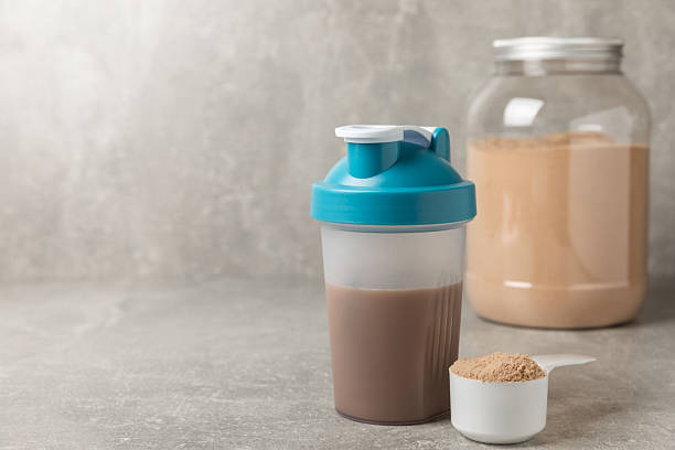 istock Protein shake with protein powder on a colored background. The powder is mixed with water or milk. A dietary supplement for a balanced diet. Whey protein. Fitness and gym diet nutrition. 2242577554