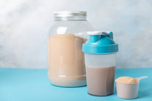 istock Protein shake with protein powder on a colored background. The powder is mixed with water or milk. A dietary supplement for a balanced diet. Whey protein. Fitness and gym diet nutrition. 2242577577
