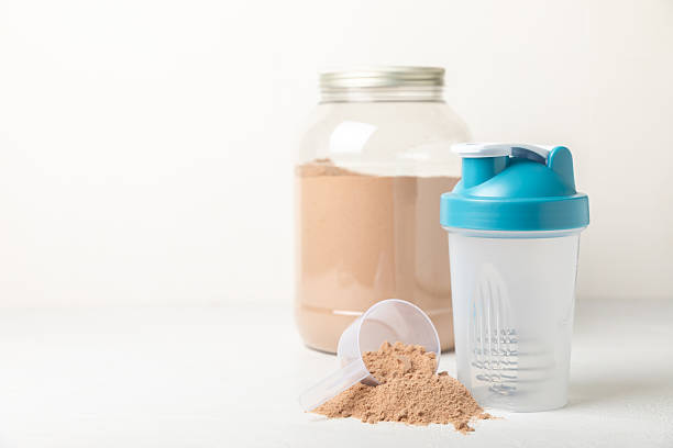 istock Protein shake with protein powder on a colored background. The powder is mixed with water or milk. A dietary supplement for a balanced diet. Whey protein. Fitness and gym diet nutrition. 2242577664