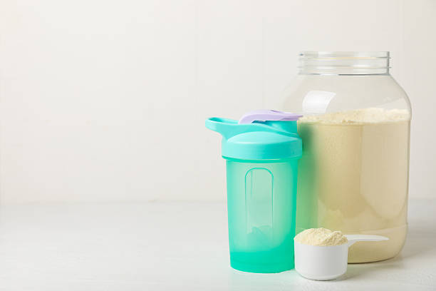 istock Protein shake with protein powder on a colored background. The powder is mixed with water or milk. A dietary supplement for a balanced diet. Whey protein. Fitness and gym diet nutrition. 2242577666