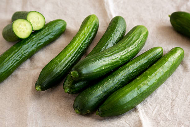 istock Organic Mini Baby Cucumbers on a white wooden background, side view. 2242577704