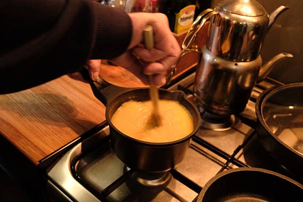 Close-up vertical shot of classic Swiss cheese fondue in hot pot, with toasted cube bread and fried beef as side dish.