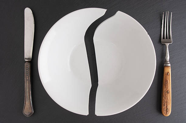 istock Broken plate with antique fork and table-knife  close up on a black background 2242579303