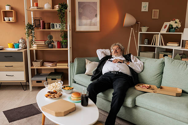 istock Overweight Man Napping While Surrounded by Junk Food 2242580565