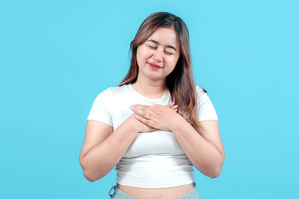 istock A young woman with a joyful expression, gently placing her hands on her heart, against a vibrant blue background, conveying warmth and positivity. 2242581062