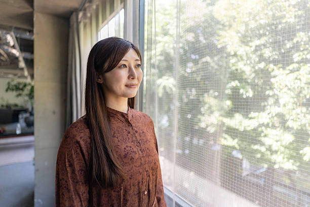 istock Portrait of woman looking through window 2242582830