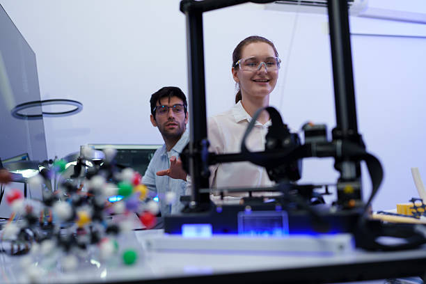 istock Engineers work with a 3D printer to print a clear white plastic model. State-of-the-art technology, selective focus, in a lab. 2242585051