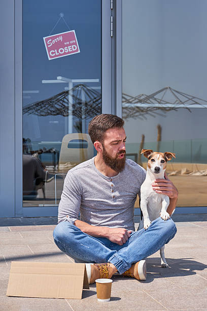 Homeless man with dog on city sidewalk seeking help