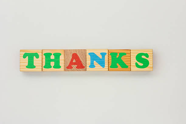 Bright wooden blocks with colorful letters to spell Thanks on a neutral surface