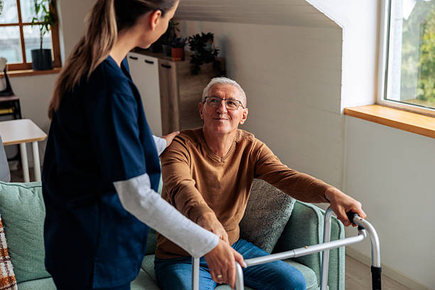 istock Nurse Assisting Senior Man to Stand Up Using a Walker 2242596147
