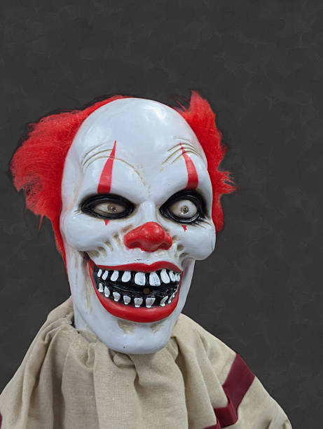 A close up of a scary clown doll in the dark of night.