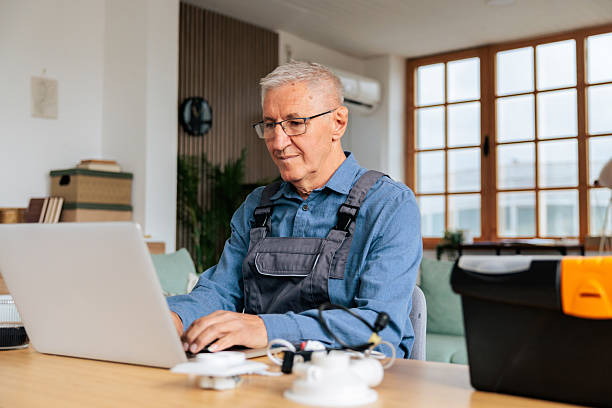 istock Senior Handyman Using Laptop While Working on Home Repairs 2242600223
