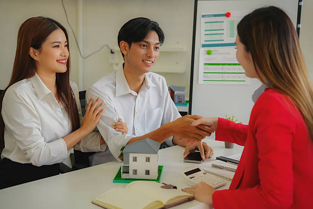 istock Two businessmen shaking hands holding documents with house model placed on table, business and investment agreement, partnership handshake, real estate deal. 2242604862