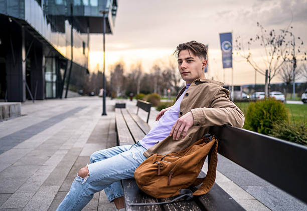istock Young man relaxing on urban bench outdoors 2242610402