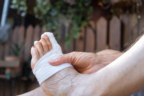 One elderly man stretching and exercising his injured foot in the back garden