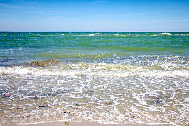 Small waves rolling on the shore of a sandy beach on a sunny day at baltic sea in germany.
