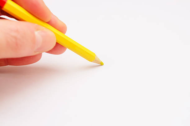 istock Hand Holding Yellow Pencil on Blank Paper Surface 2242629183