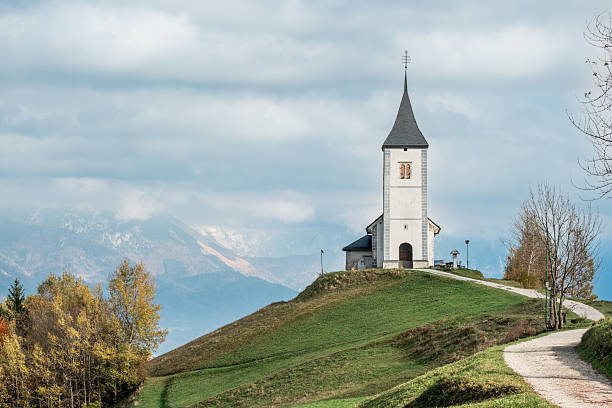 istock Church on a grassy hill with mountains in the background. 2242629263