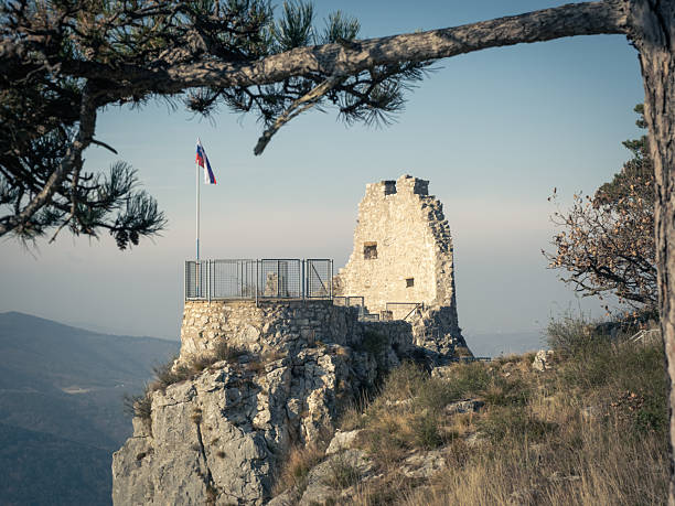 istock Ruined castle on a rocky cliff with a flag. 2242629875