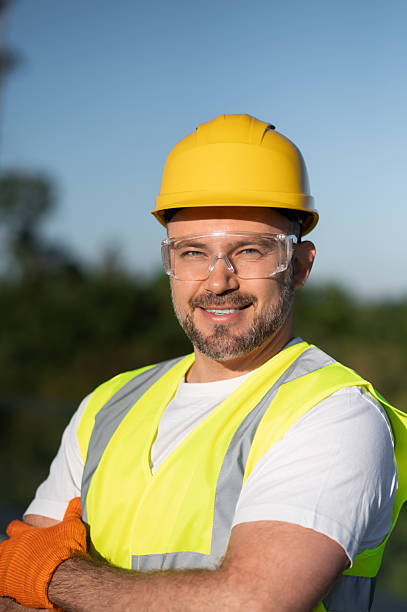 istock Man in helmet and vest standing on rooftop with solar panels behind 2242631981