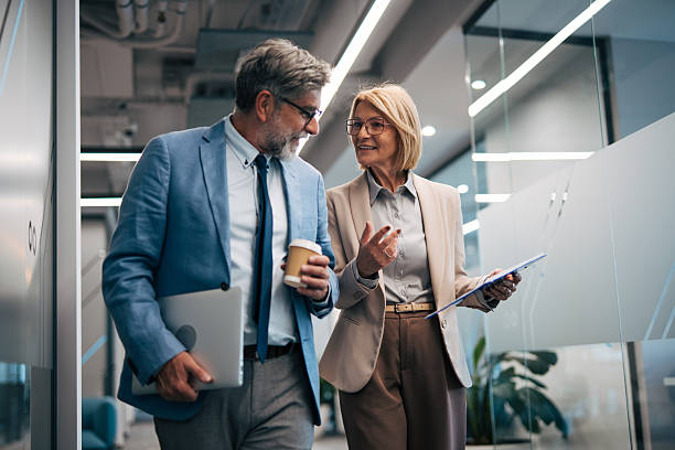 istock Mature business colleagues discussing work while walking in office 2242632620