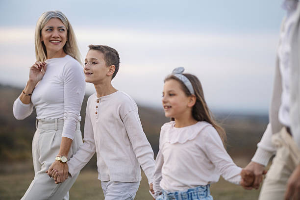 istock Family walking outdoors holding hands enjoying togetherness 2242635517