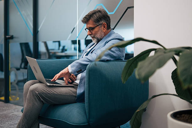 istock Senior businessman working on laptop in modern office lounge 2242637175