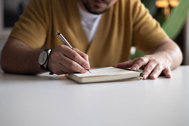istock Close-up of Man Writing in a Notebook at a Desk 2242637794