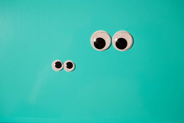 Minimalist composition of googly eyes on teal background